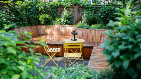 Cozy backyard patio with wooden seating, yellow table and chairs