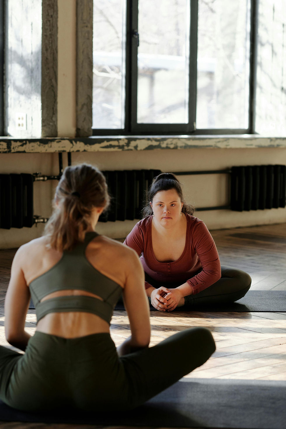 Two women in yoga poses, sitting in a studio