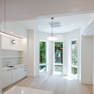 Sunlit rear bay windows beside custom white built-in cabinetry and a beverage sink