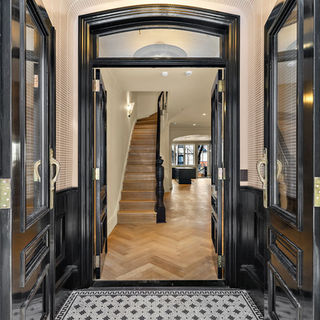Restored vestibule with mosaic tile flooring and a view of the oak staircase.
