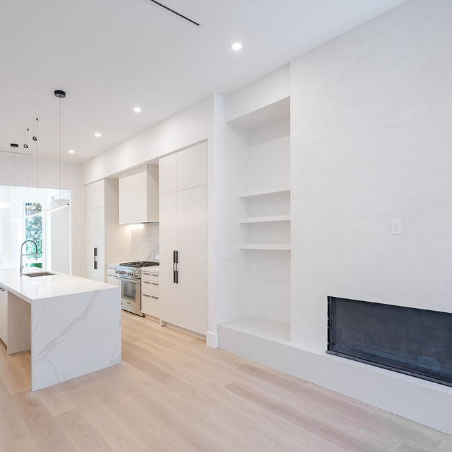 Open living area connecting the linear fireplace, custom kitchen and rear bay windows