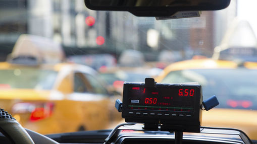 A close-up of a taxi meter showing the fare increasing, while the vehicle appears stationary, symbolising wasted motion and hidden costs.