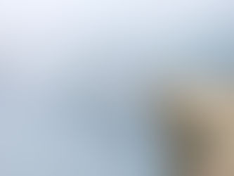 Person standing on a mountain peak at sunrise, looking into a misty, uncertain landscape—symbolising leadership under uncertainty.