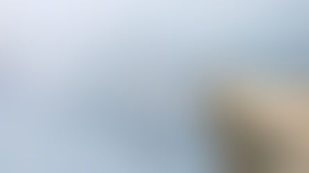 Person standing on a mountain peak at sunrise, looking into a misty, uncertain landscape—symbolising leadership under uncertainty.