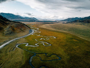 Overhead view of a windy river system next to a clean, structured road, symbolising organisational clarity.