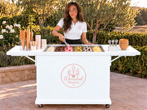 Lauren standing behind the white Decadent Desserts cart at an outdoor event.