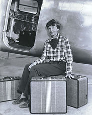 Amelia Earhart sitting on her branded luggage next to a plane