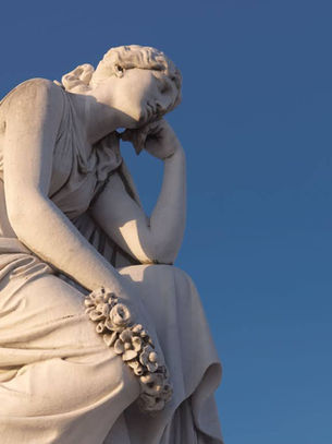 A classical-style marble statue of a woman sitting and leaning pensively on one hand.