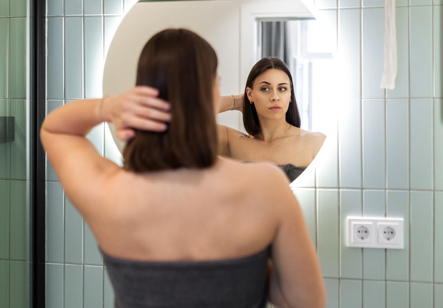 Junge Frau vor Badezimmerspiegel