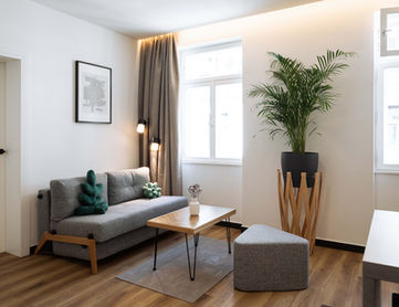 Wohnzimmer Urban Jungle Apartments Wien mit Pflanzen, Sofa und Couchtisch