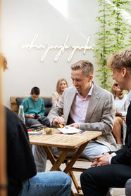 Junge Männer beim Kartenspiel auf der Terrasse im Urban Jungle Garden