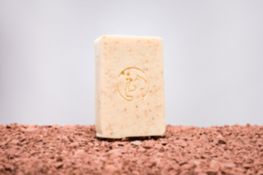 Savon à l'avoine et au miel de l'Aveyron. Le savon est posé sur de la terre rouge de Camarès.