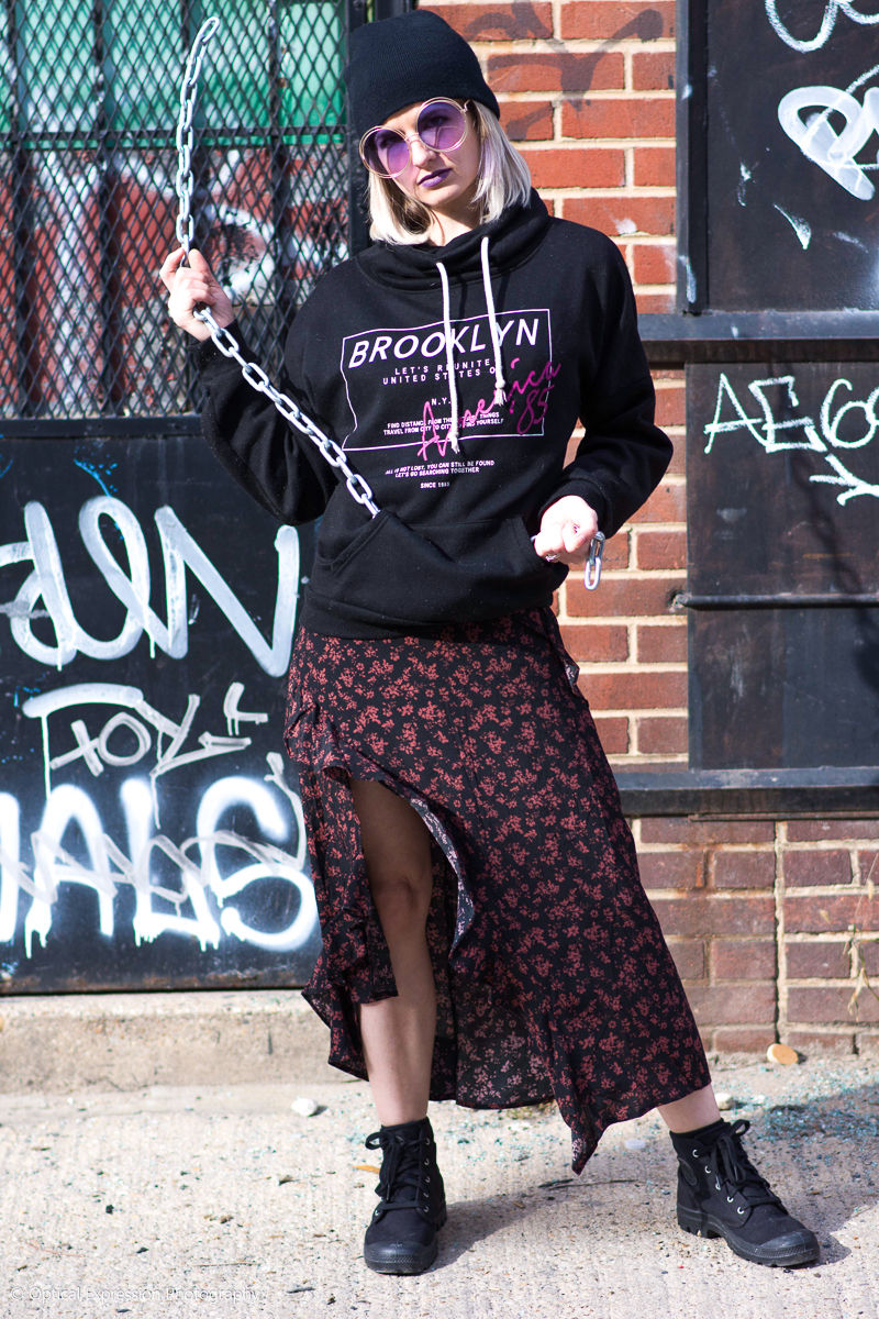 Model in urban wear with sunglasses and chain.
