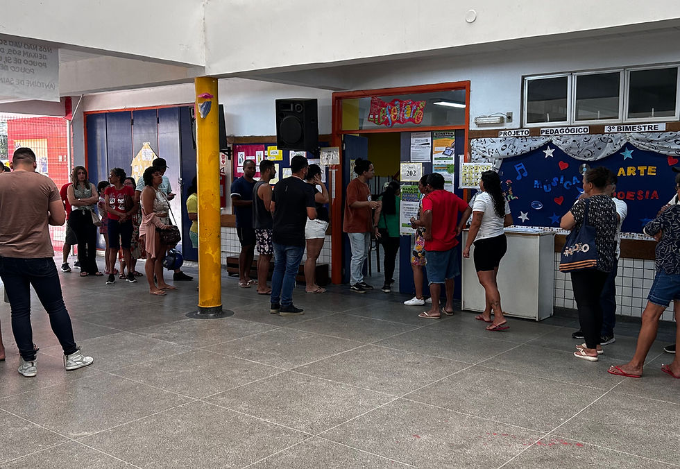 Na imagem podemos ver pessoas pessoas aguardando para votar dentro de um local de votação.