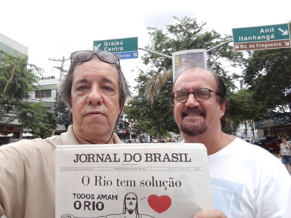 Na imagem podemos ver Jorge da Costa Pinto mostrando um jornal para câmera, ao lado dele está Guilherme, os dois homem aparentam ter mias de 50 anos de idade, Guilherme é um homem branco, de cabelos pretos e com calvície, usa uma barba no formato cavanhaque e óculos de armação redonda. Jorge é um homem branco de cabelos grisalhos. Os dois estão no centro do bairro da Freguesia.