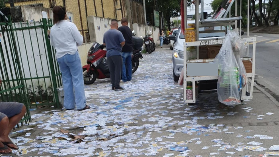 na imagem podemos ver uma rua suja com santinhos de candidatos