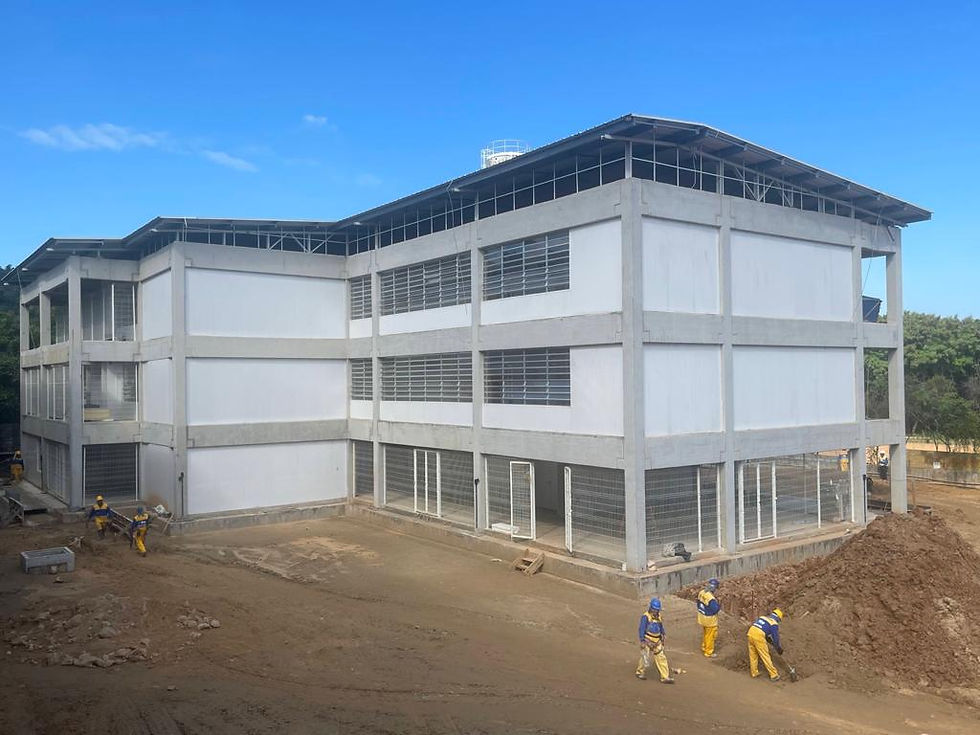 Na imagem podemos ver um grande prédio de três andares que abrigará as escolas, funcionários trabalham na obra.