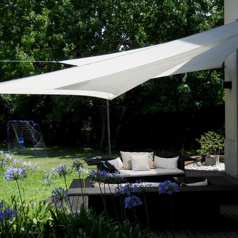 dos (2) velas blancas que se superponen una de la otra con un diseño unico hecho a medida, cubriendo una galeria al aire libre rodeada de flores violetas y el pasto verde.