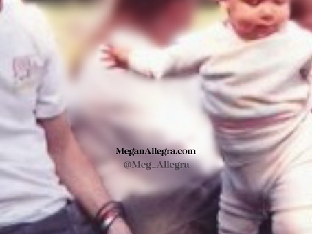 A baby stands beside her father.