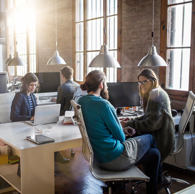 Man and woman sat down talking in office brick walls