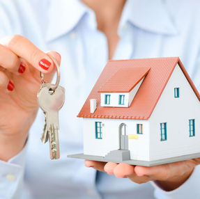 Holland Michigan Realtor handing over house keys with a model home, representing home buying services by Garrett Senters of Five Star Real Estate Leaders.