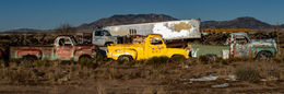 Vintage trucks parked in a desert landscape with mountains and dry grass