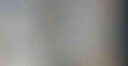 Person standing by a building with repeating windows and geometric architectural patterns