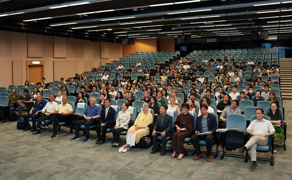Audience are seated in a lecture hall during the presentation.