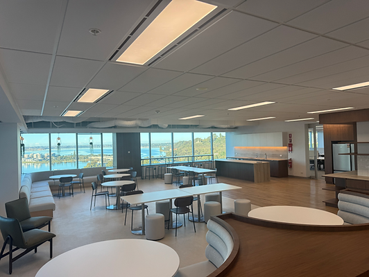 Open office space with tables, chairs, and expansive city and water views.