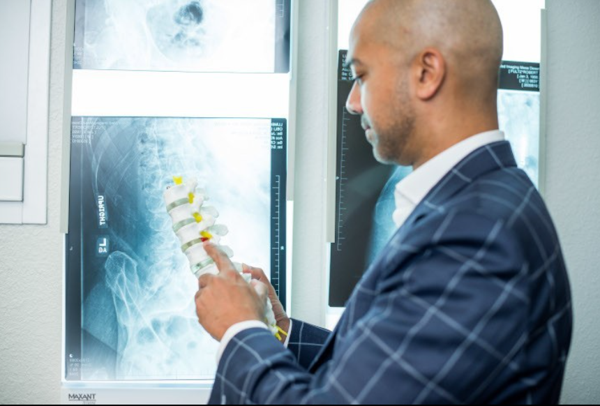 Orthopedic Spine Surgeon Dr. Rafath Baig explaining L4-L5 lumbar spine anatomy using a bone model.