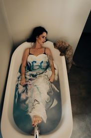 a woman in a bath with a dog looking on