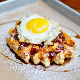 Our golden Liége waffle smothered with melty cheddar cheese, bacon crumble, maple syrup, and topped off with a fried or scrambled egg.