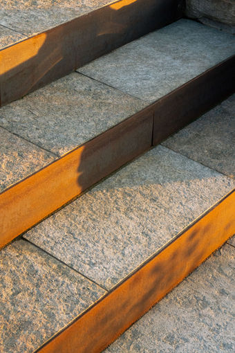 Granittreppe mit orangefarbener Cortenstahl-Kante, Architekturdetail für Brand-Fotografie