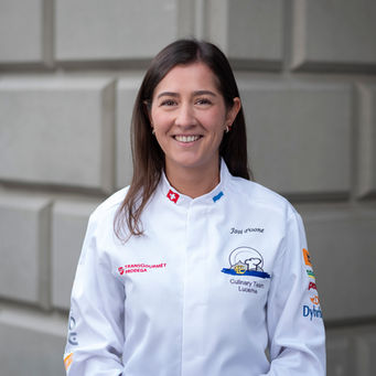 Lächelnde Köchin in weisser Kochjacke vor Steinwand, Business-Portrait für Gastronomie