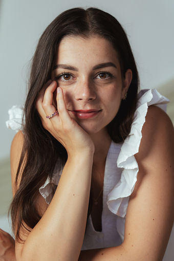 Frau mit Rüschenbluse stützt das Gesicht in die Hand, persönlicher Portraitshoot