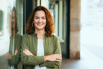 Lächelnde Frau in grünem Hemd mit verschränkten Armen vor Schaufenster, Business-Portrait Luzern