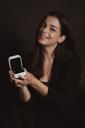 Lächelnde Frau hält eine kleine weisse Schmuckbox in der Hand, Produktfotografie mit persönlicher Note