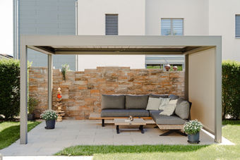 Pergola mit Sitzgruppe vor Natursteinwand im Garten, Fotografie für Unternehmen in Luzern