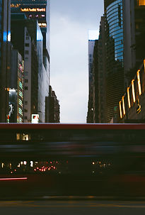 Hochhäuser in der Dämmerung mit Lichtspuren auf der Strasse, urbane Fotografie von unterwegs