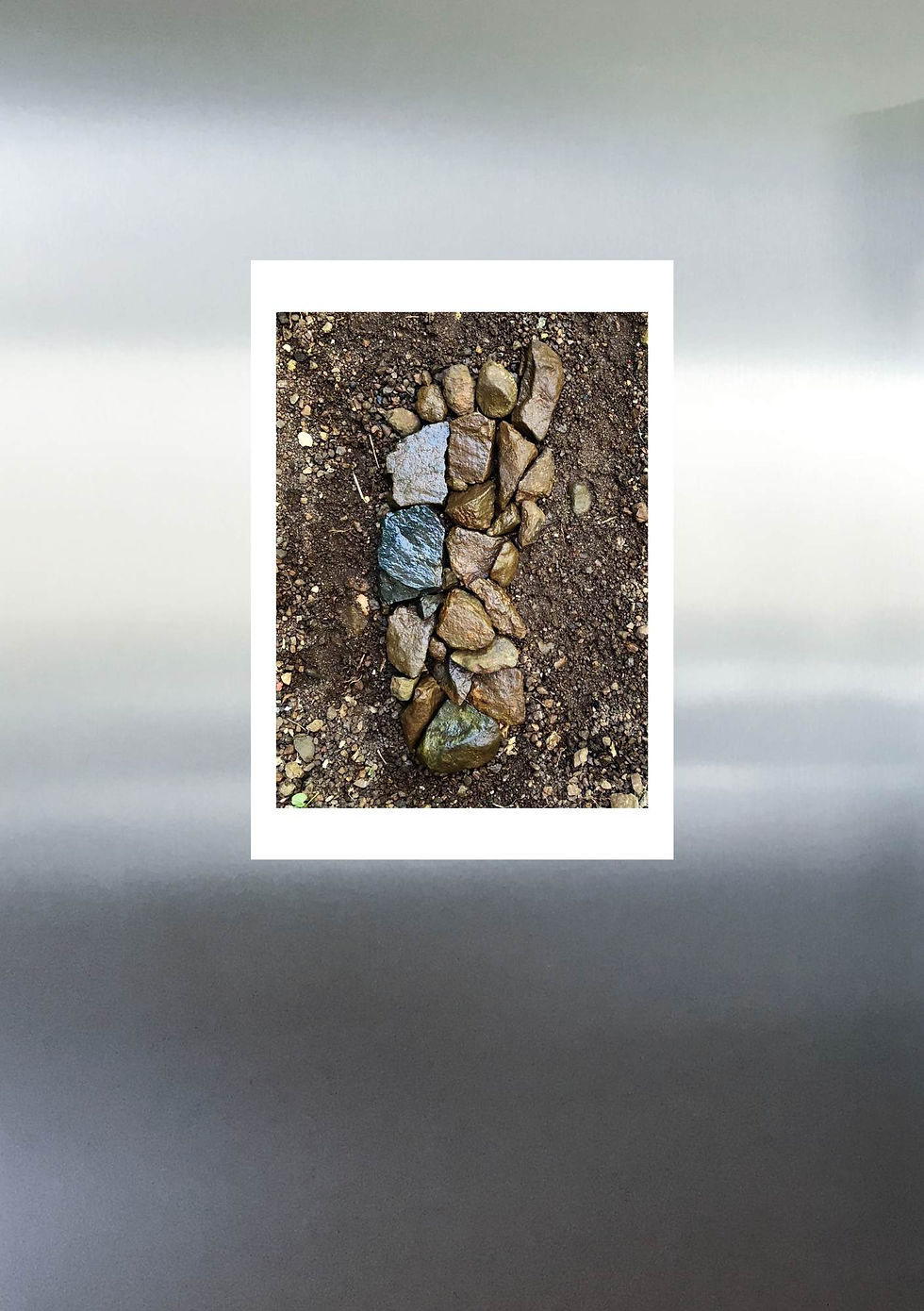 Thumbnail: A5 card with image of sculpture of foot made of stones displayed on fridge