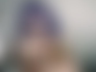 Kat Joplin with bold makeup and purple hair, sitting in a bathtub holding colourful roses.