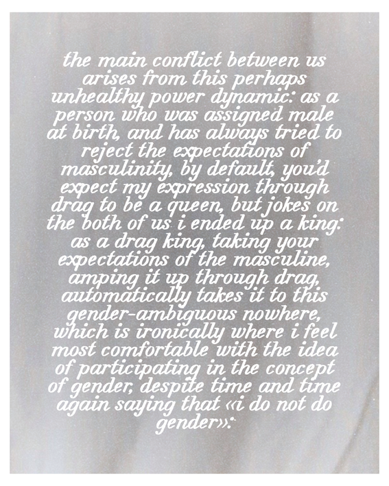  A text-only image on a pale grey fabric background, featuring a personal essay excerpt about being a drag king and navigating gender identity and expectations, in white cursive type.