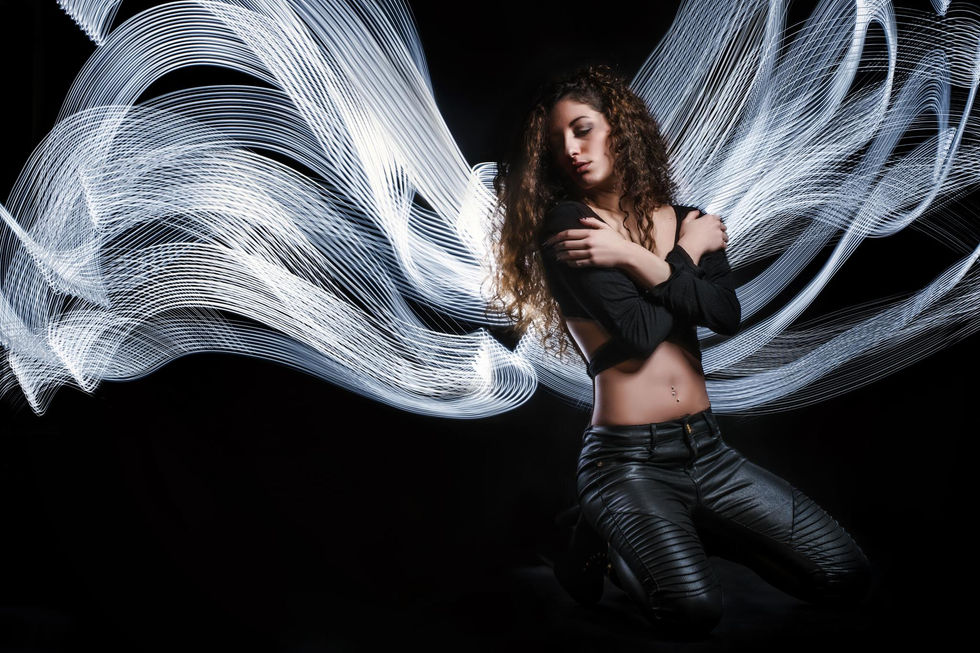 Donna con capelli ricci e scie luminose bianche a forma di ali.