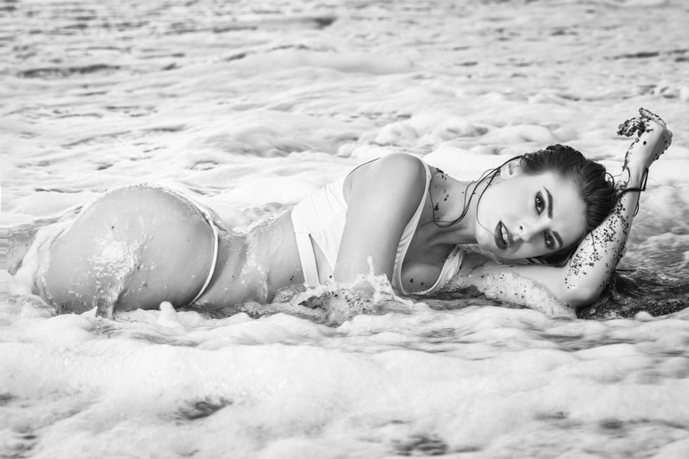 Modella in bikini distesa tra le onde del mare