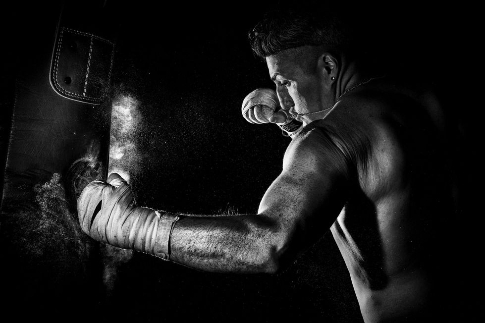 Pugile che colpisce un sacco da boxe in bianco e nero.