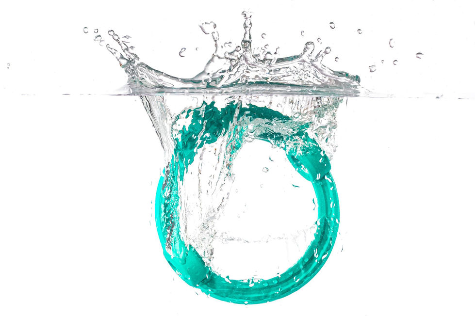Anello verde acqua immerso in acqua con schizzi dinamici