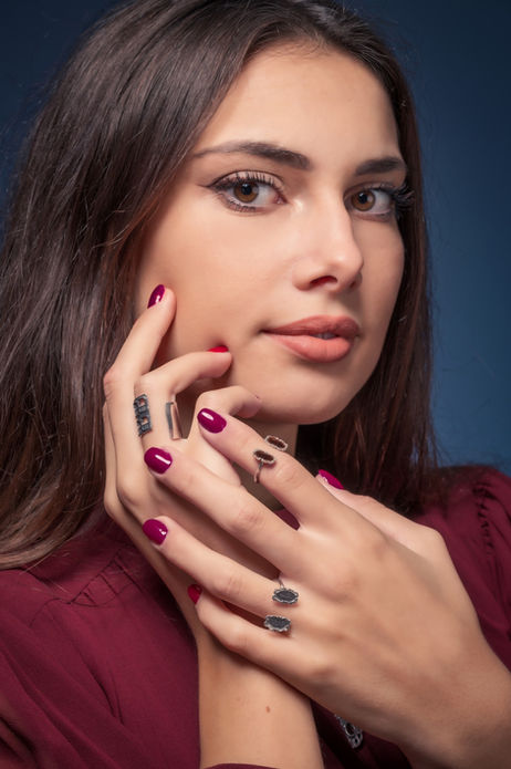 Ritratto di una giovane donna con smalto rosso e anelli.