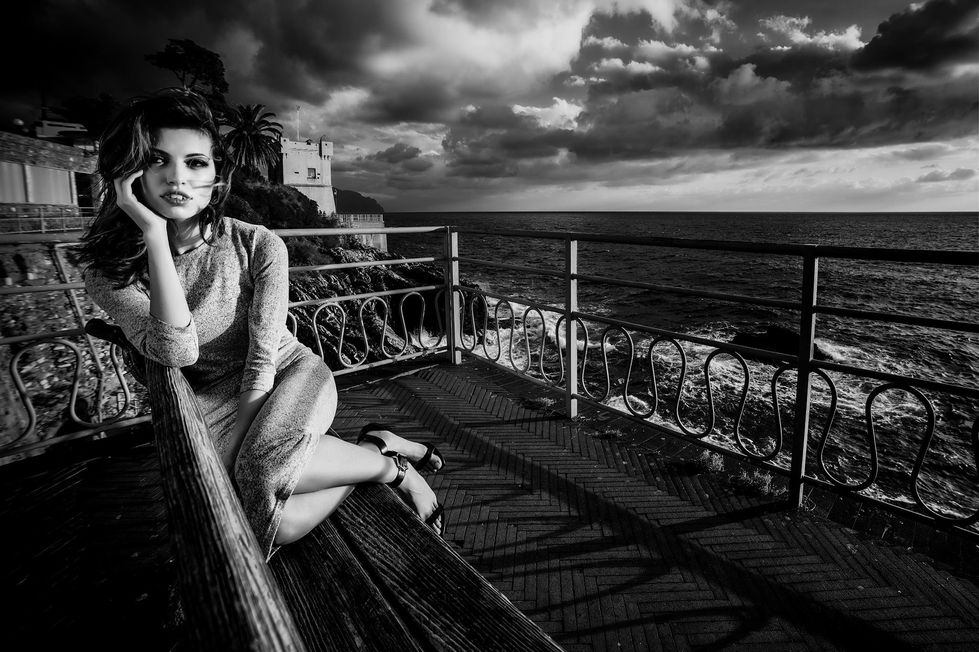 Donna seduta su una terrazza panoramica affacciata sul mare.
