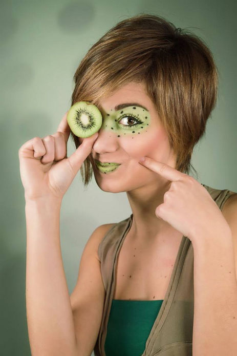 Donna con trucco artistico al kiwi e fetta di kiwi sull'occhio