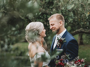 Groom looks into brides eyes while standing in a vineyard
